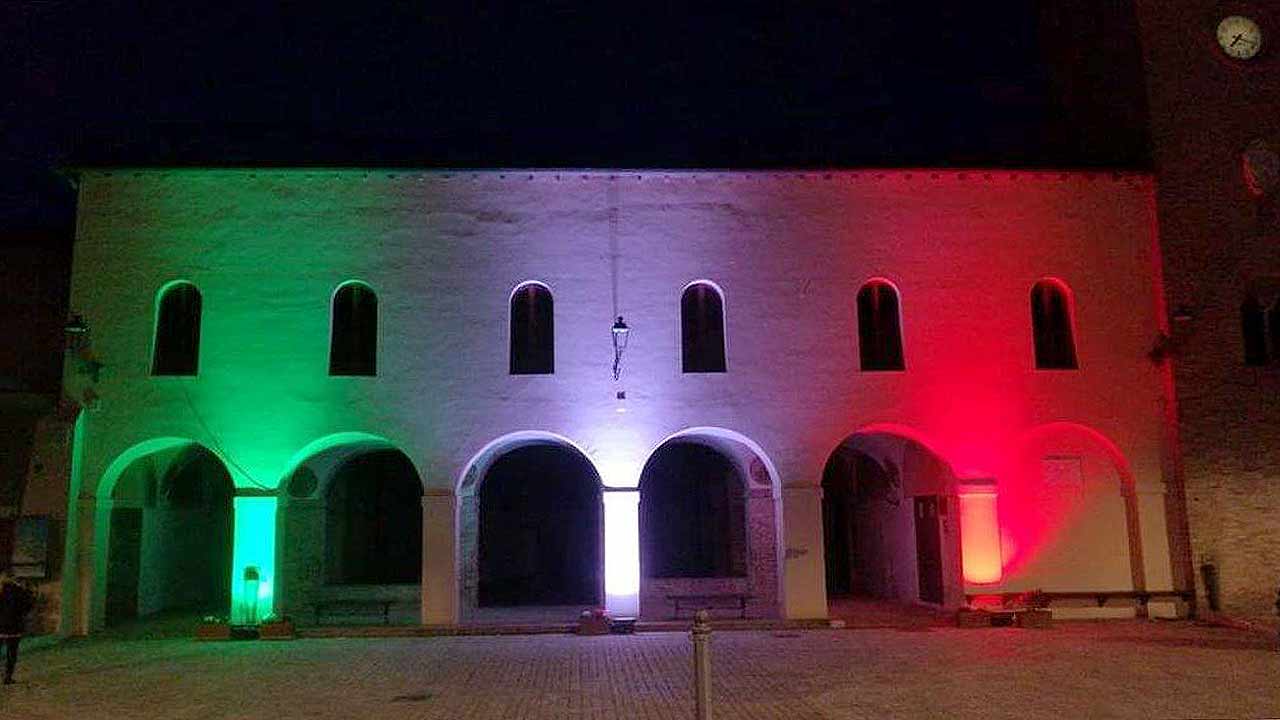 Il tricolore illumina la facciata dell’ex convento San Francesco al Mercatale, nella centrale piazza della Libertà a Ostra Vetere