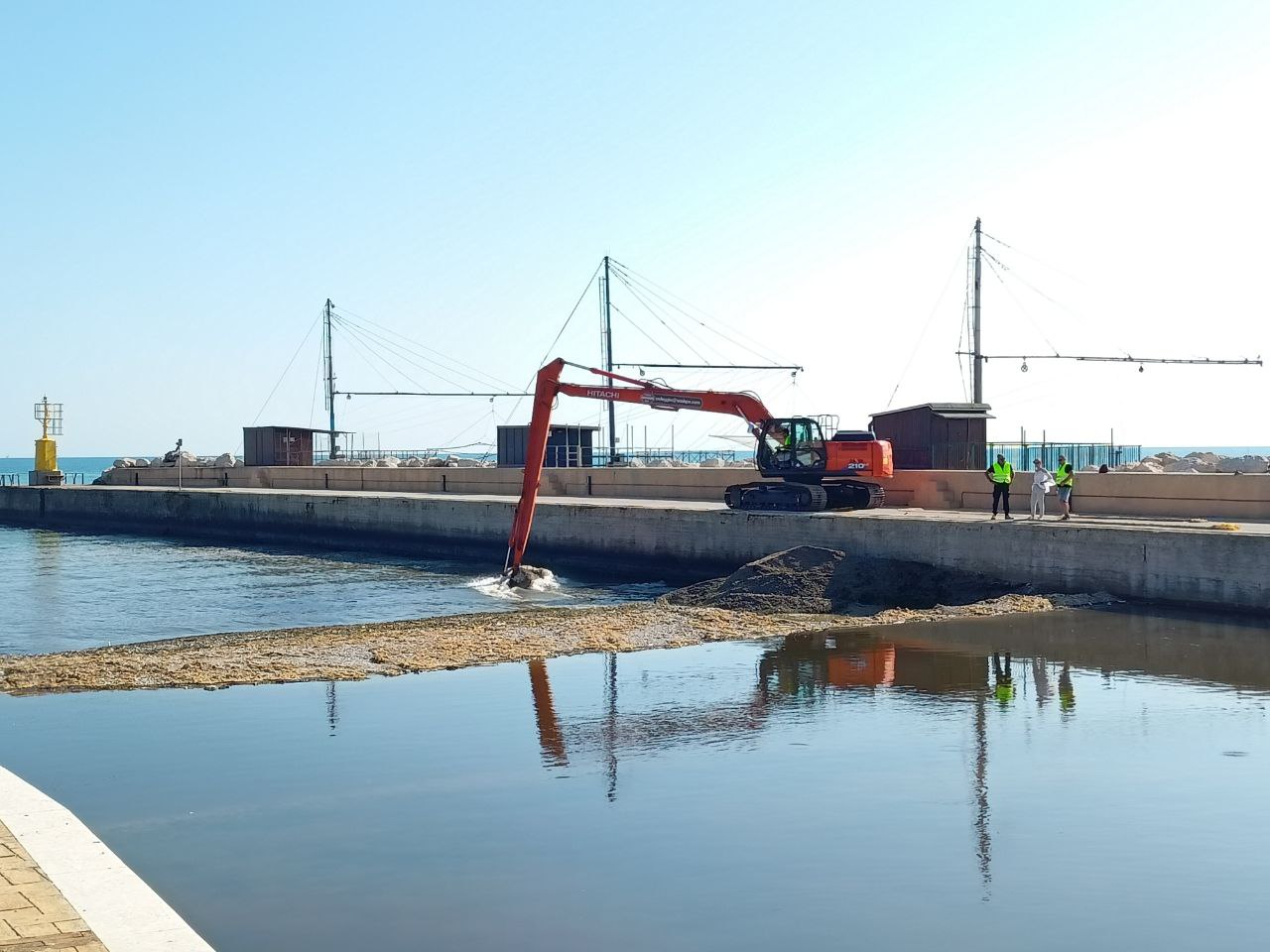 I lavori per aprire un varco nella diga naturale di ghiaia e detriti formatasi alla foce del fiume Misa a Senigallia